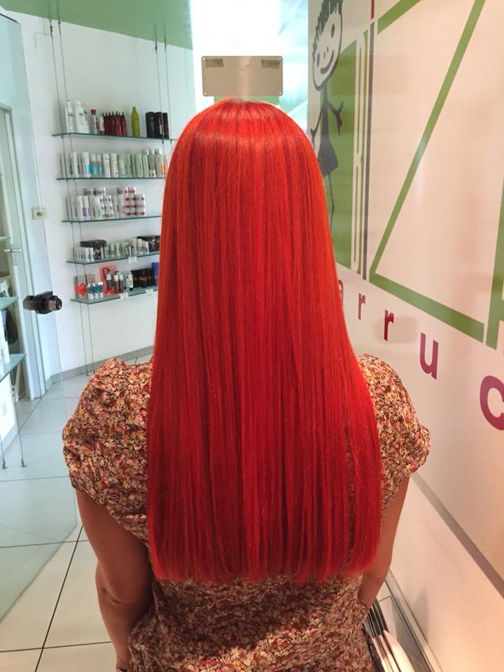 Donna con lunghi capelli lisci e di un rosso acceso, in piedi in un salone.