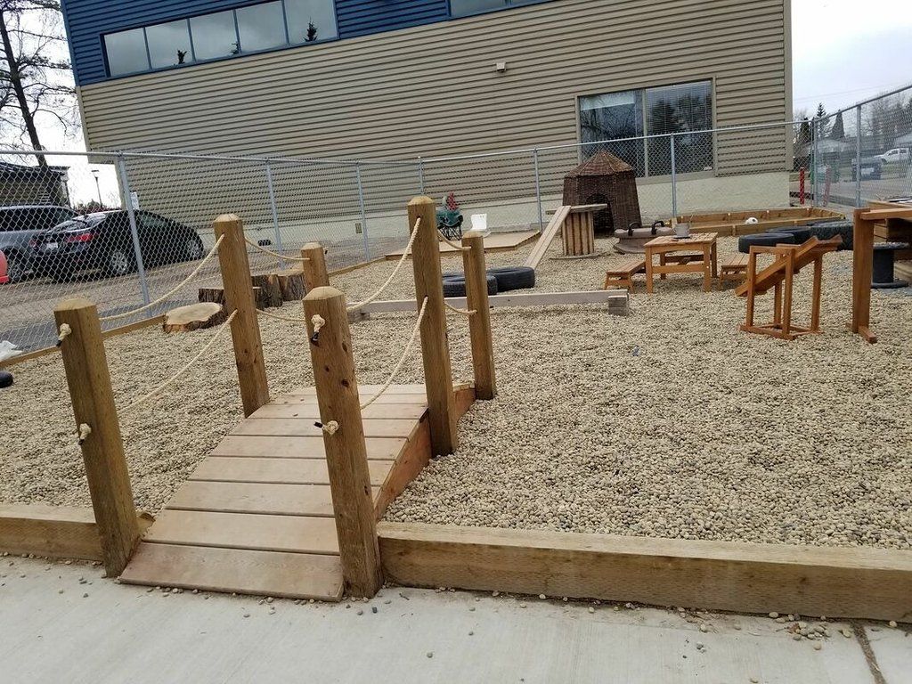 There is a wooden bridge in the middle of a playground.