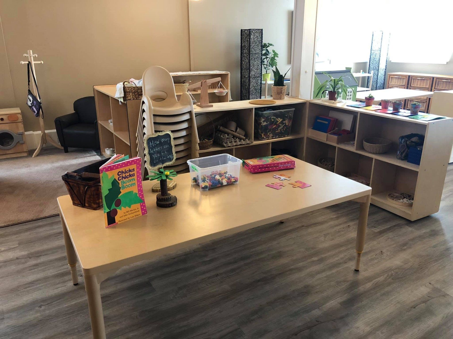 A room with a table and shelves filled with toys and books.