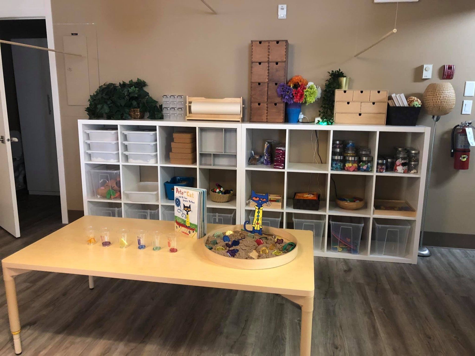 A room with a table and shelves filled with toys.