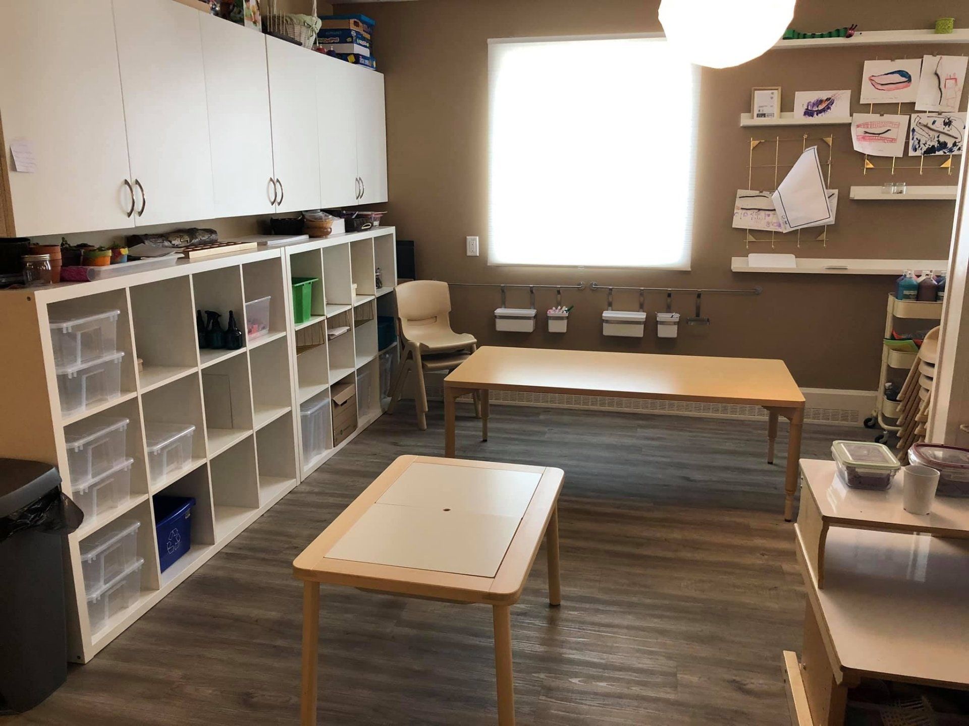 A room with tables , shelves , chairs and a window.