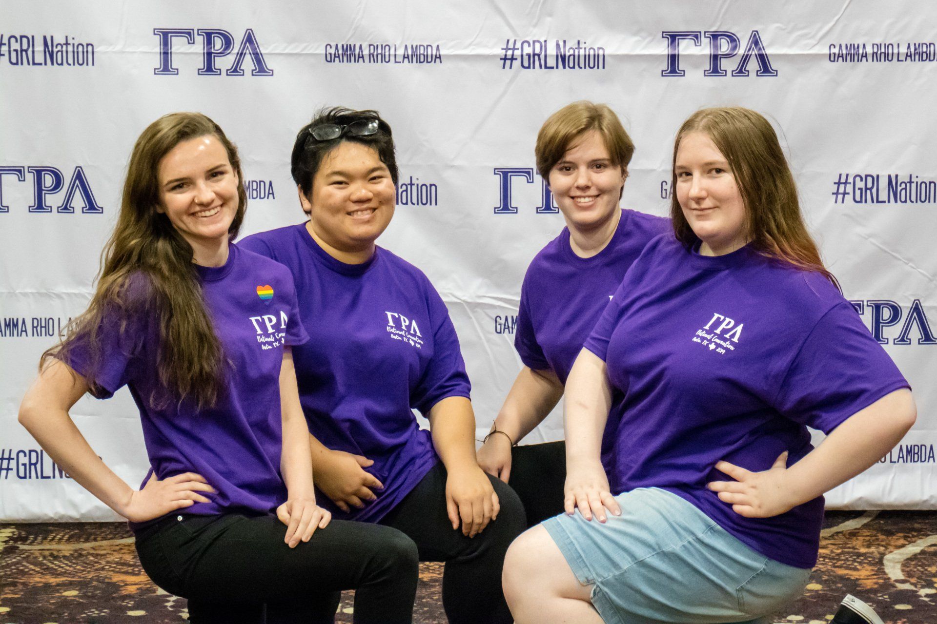 A group of 4 people pose together in front of a background with text.