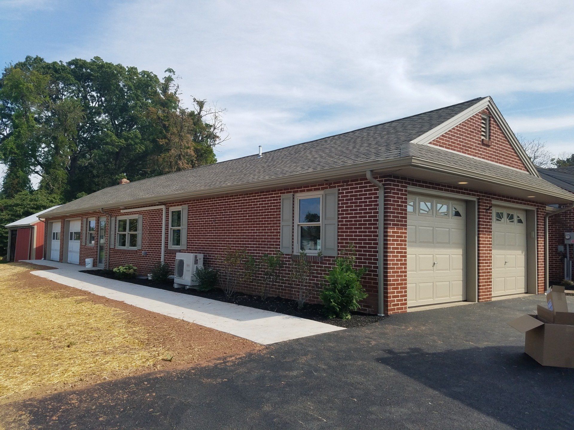Brick building with garage doors, windows, and a paved walkway.