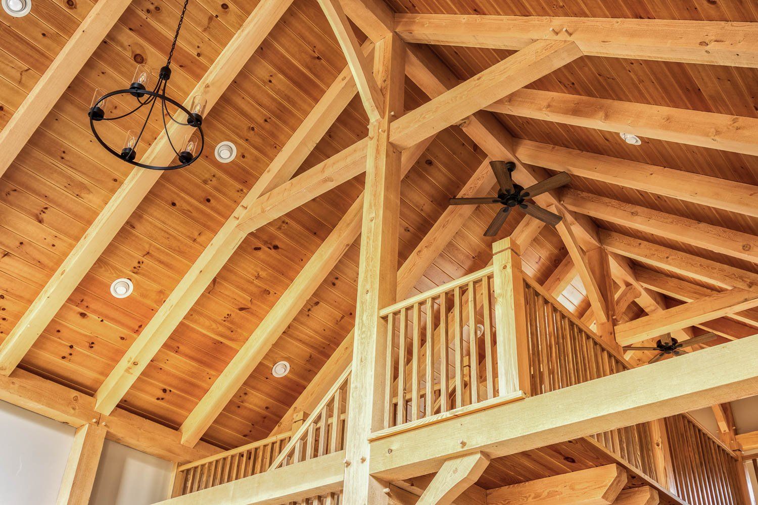 Wooden interior of a building, showing exposed beams, ceiling, and balcony.