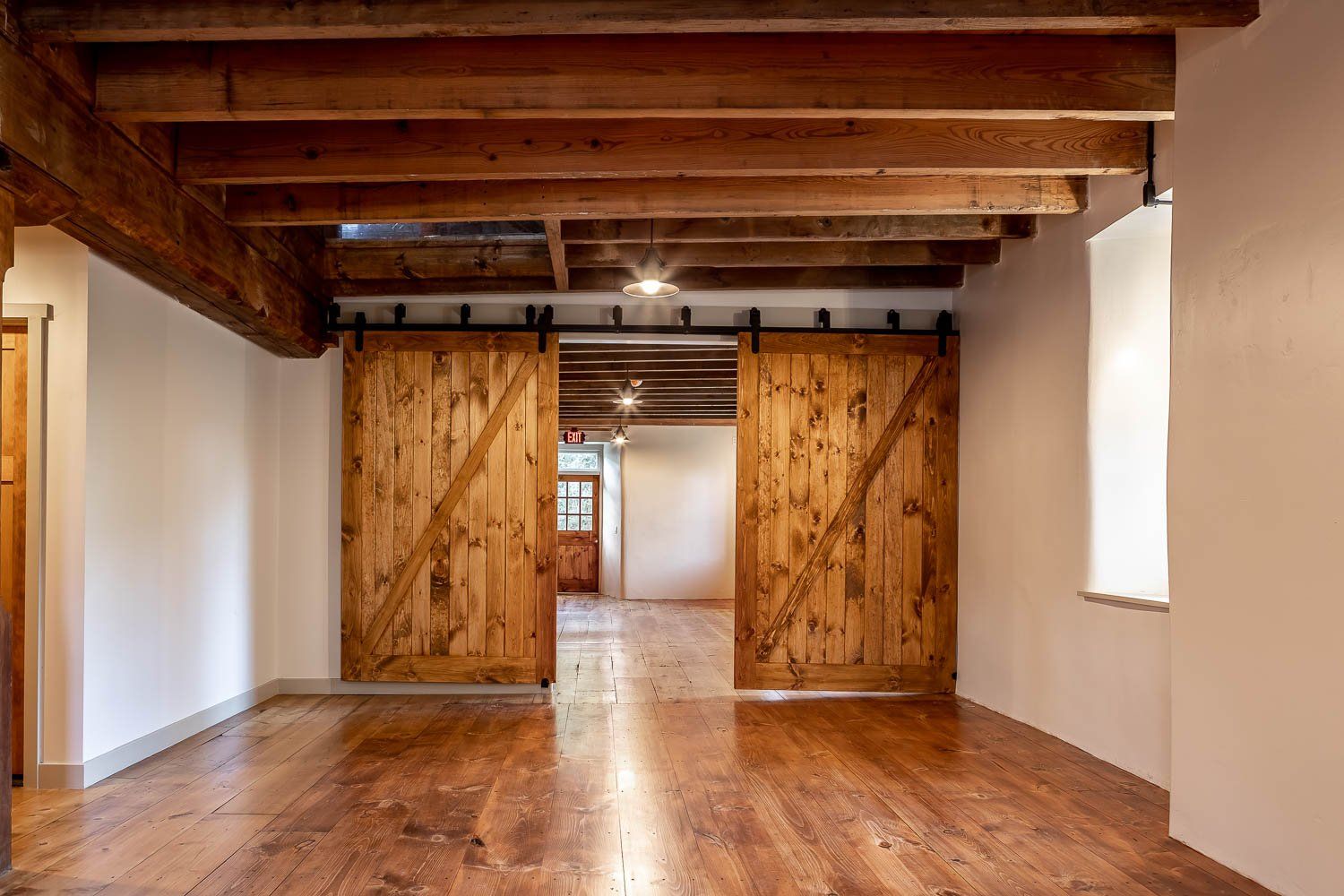 Wooden interior with barn doors, exposed beams, and hardwood floors.