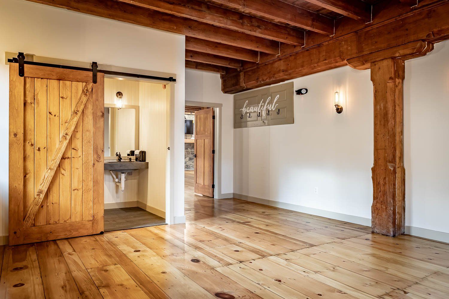 Rustic interior with wood floors, exposed beams, barn door to bathroom, and 