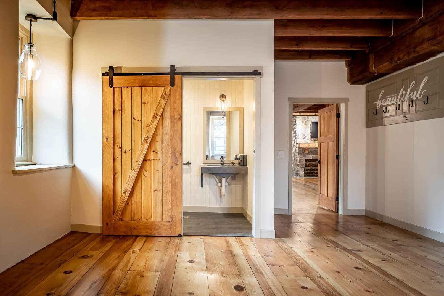 Rustic interior with wood floors, a sliding barn door, and a bathroom visible.