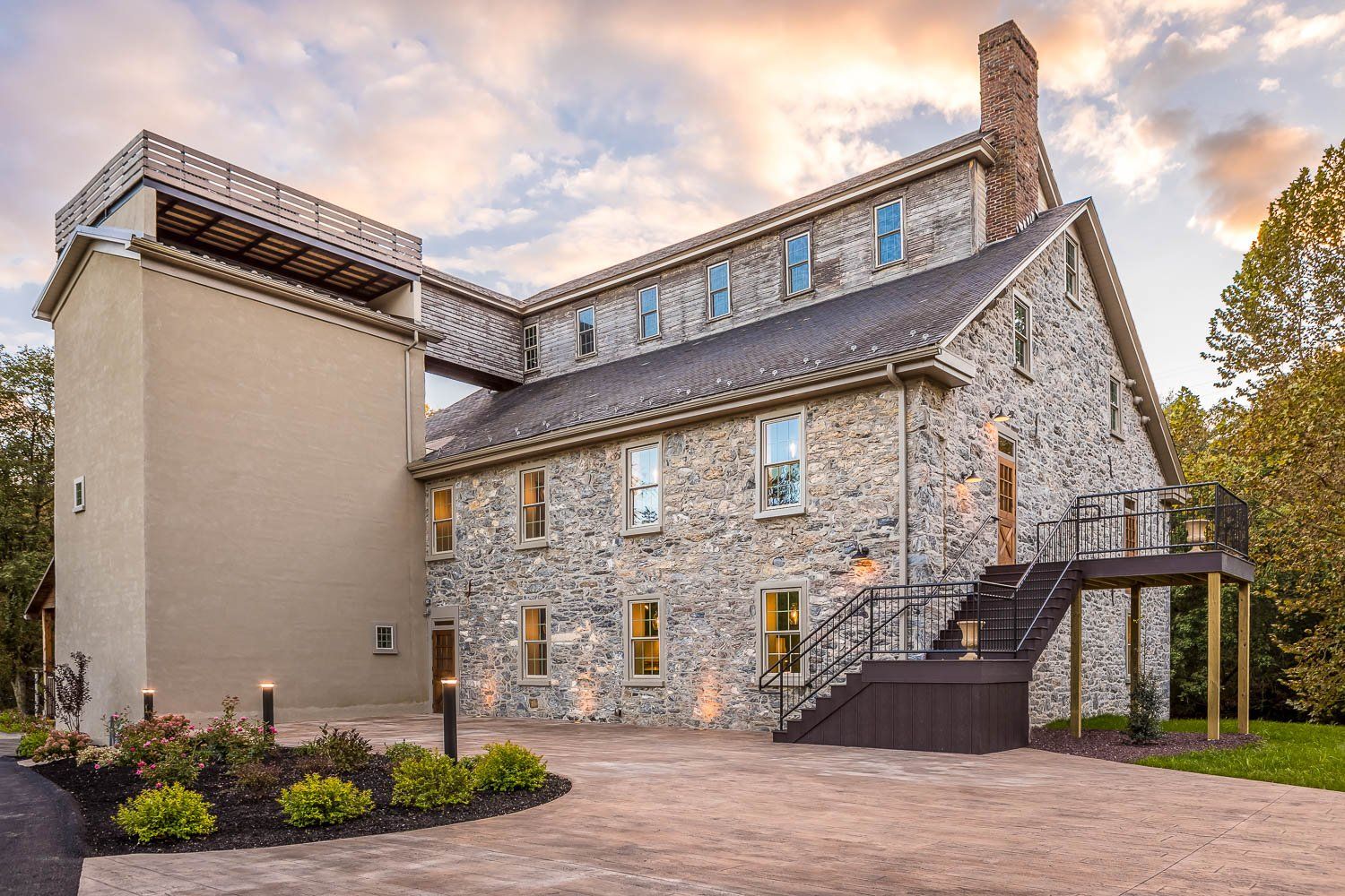 Stone building with connected tower and walkway, dark stairs, and landscaped area.