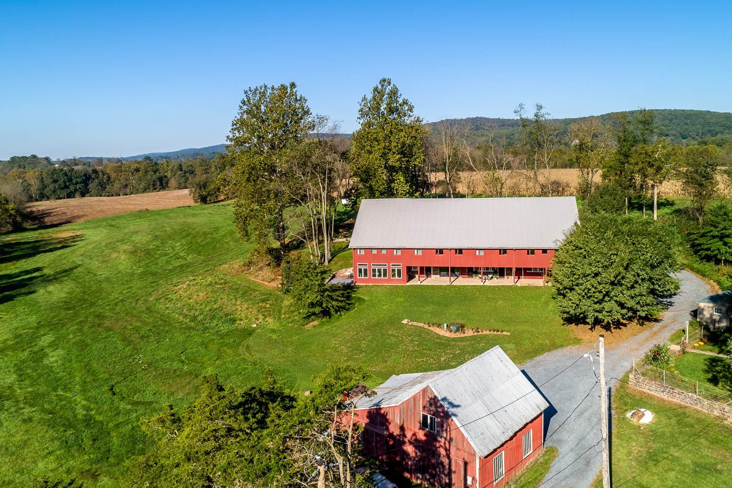 Red barn and outbuilding on a green hillside with a blue sky.