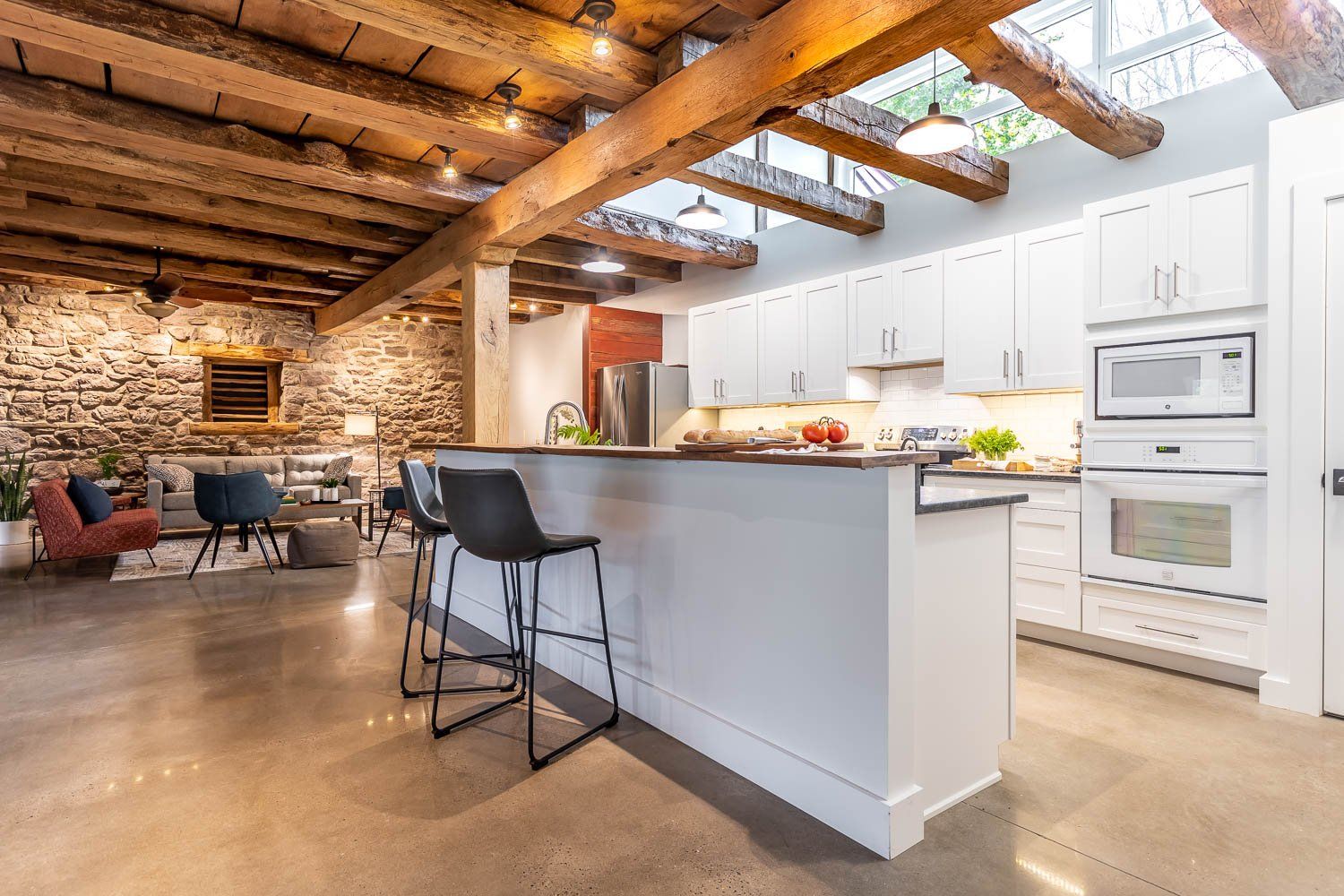 Modern kitchen with white cabinets, breakfast bar, and exposed wooden beams.