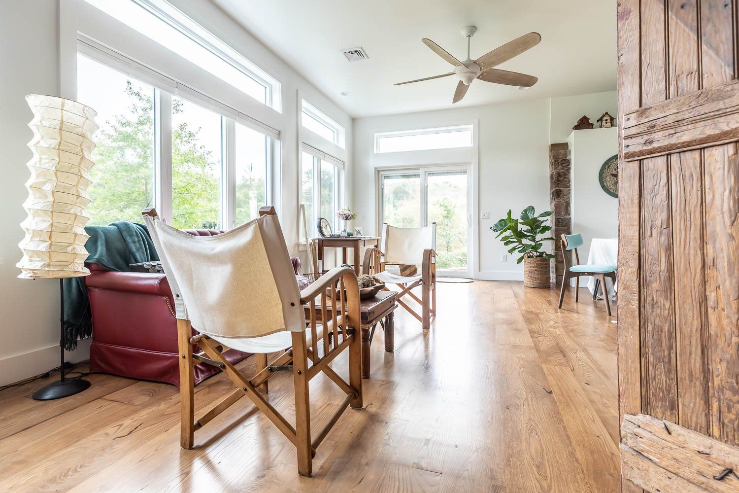 Bright living room with wood floors, large windows, and vintage furniture.