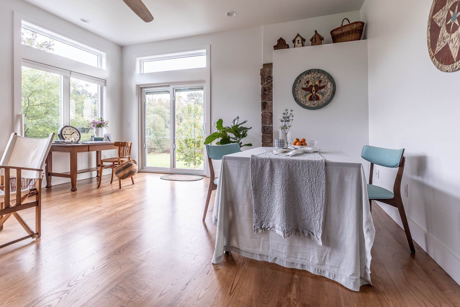 Bright dining room with wooden floors, table set for two, and large windows.