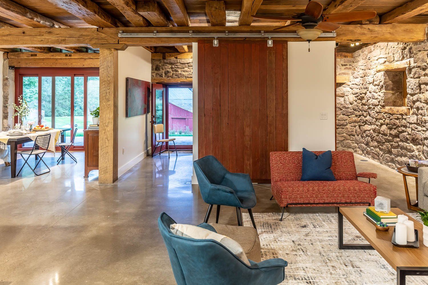 Living room in a rustic space with stone walls, wooden beams, and colorful furniture.