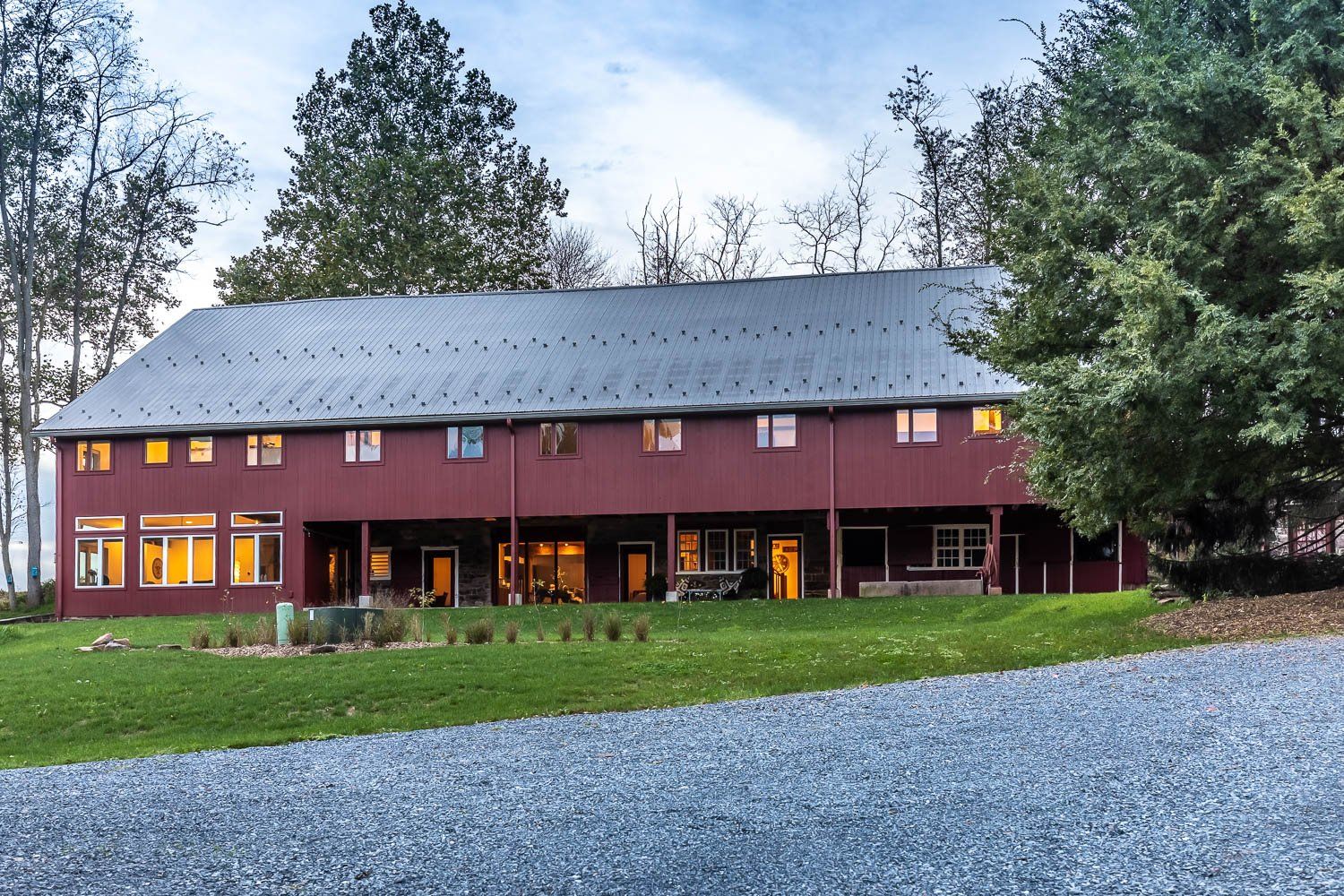 Red two-story building with a gray roof, surrounded by trees and a green lawn.