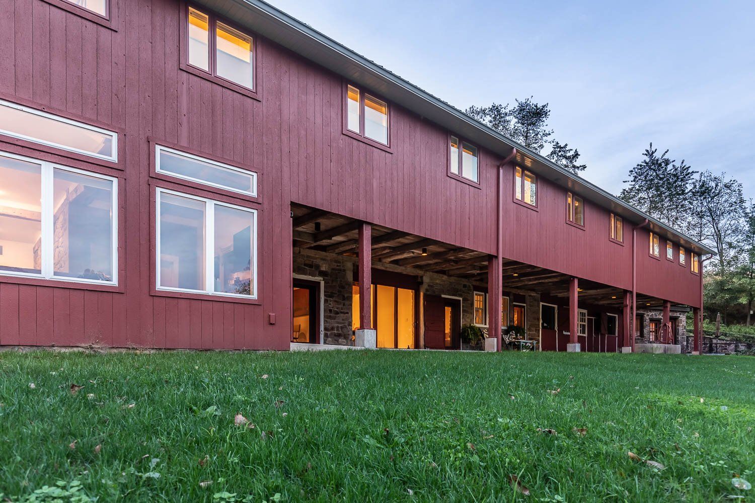 Red two-story house with large windows, set in a grassy yard.
