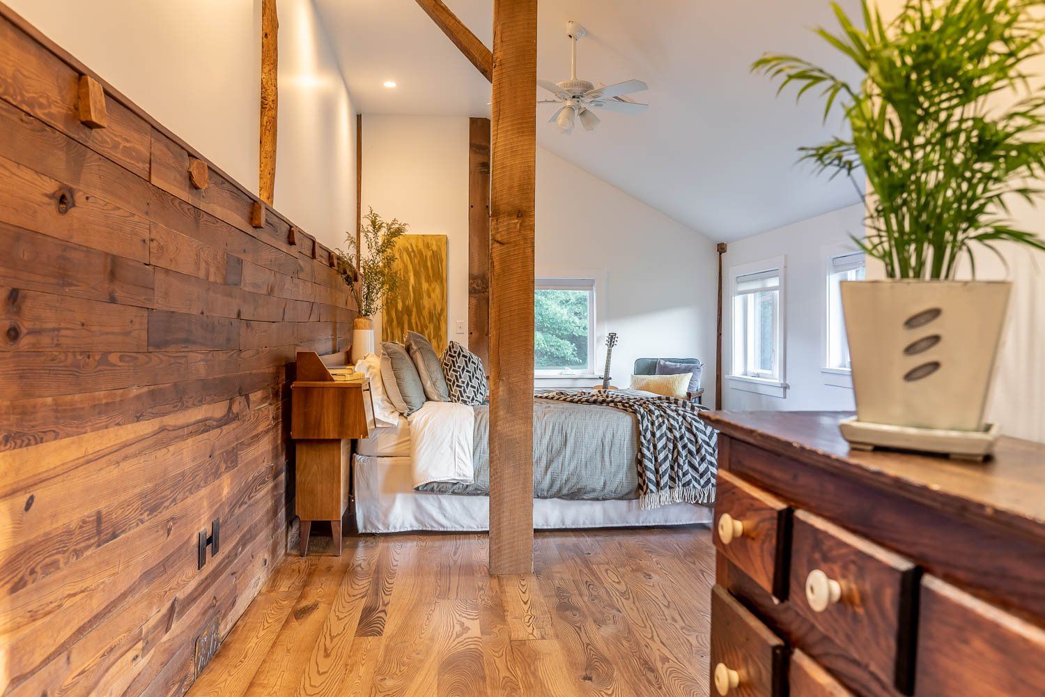 Bedroom interior with exposed wood beams, wooden wall, and a bed.