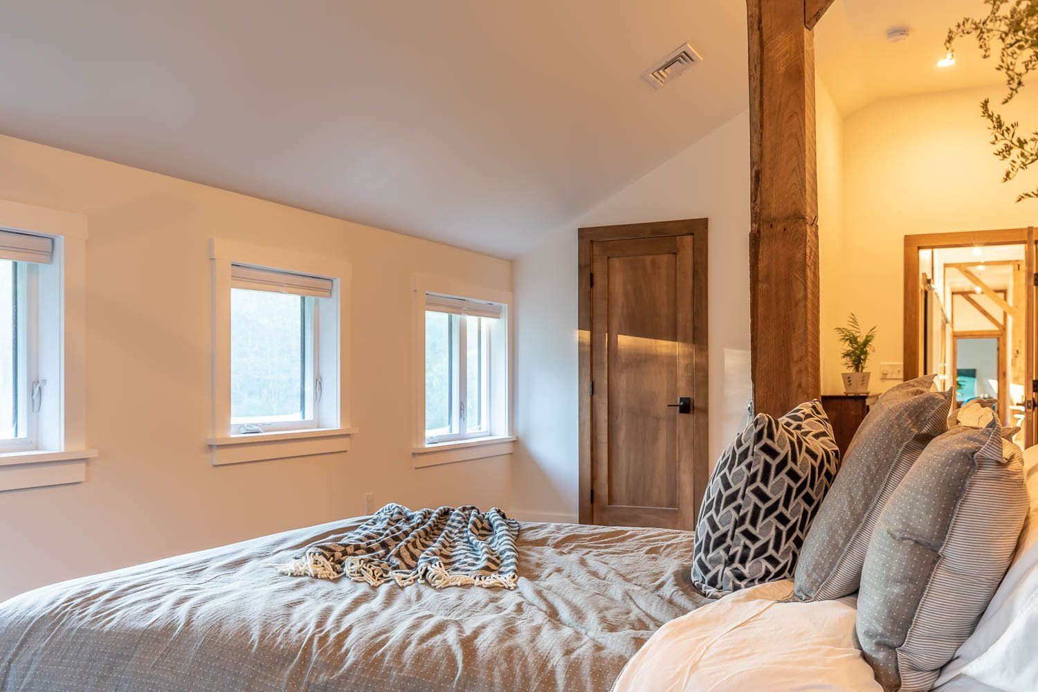 Bedroom with bed, windows, wooden door, and rustic accents.
