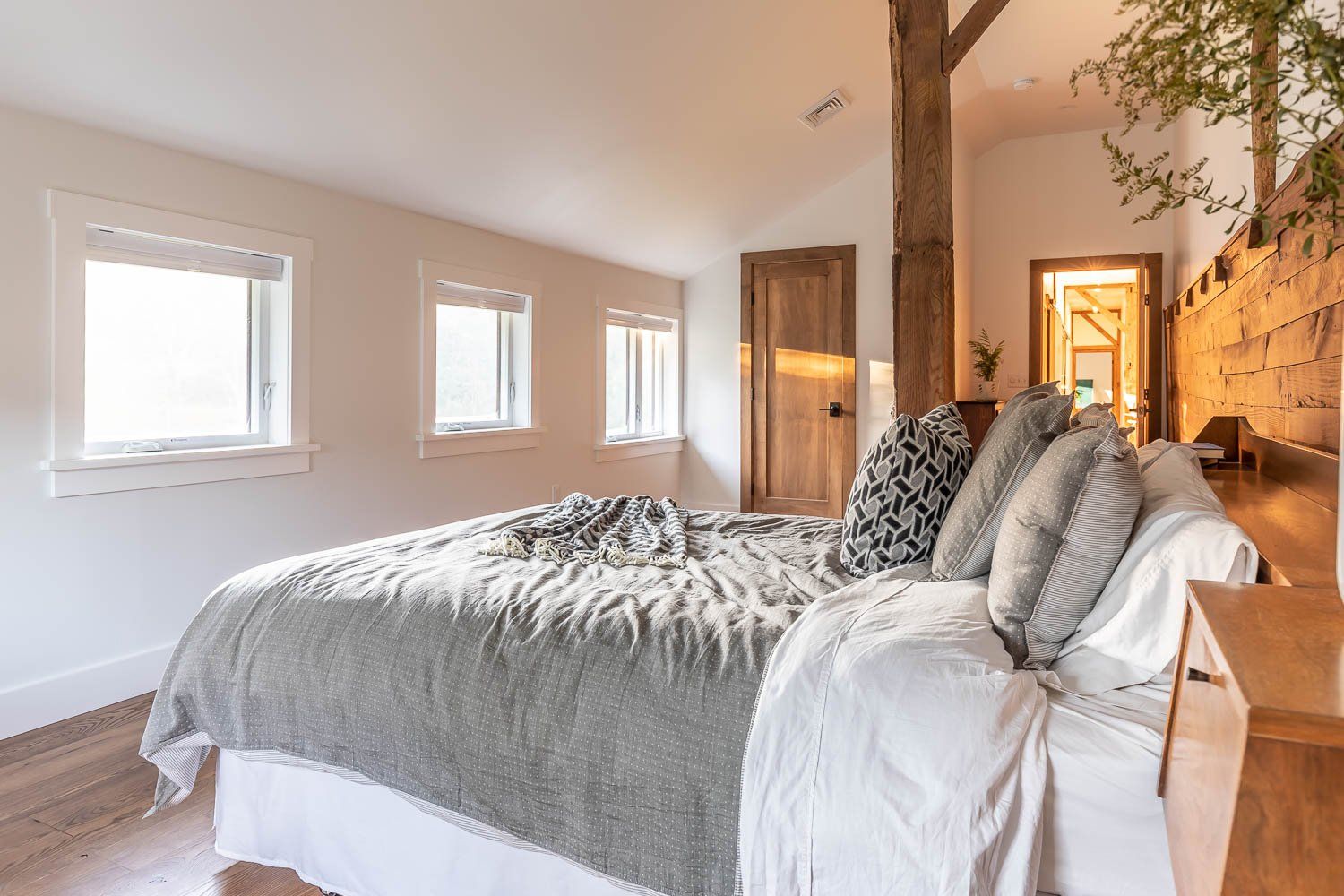 Bedroom with bed, windows, and wooden accents.