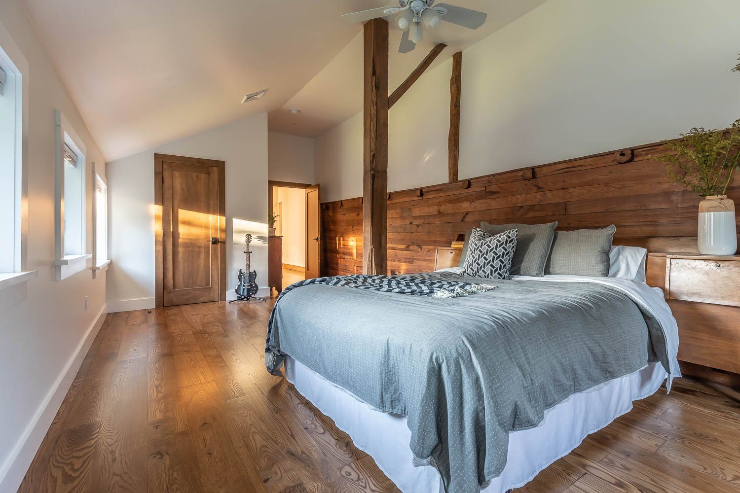 Bedroom with wooden headboard, hardwood floor, natural light.
