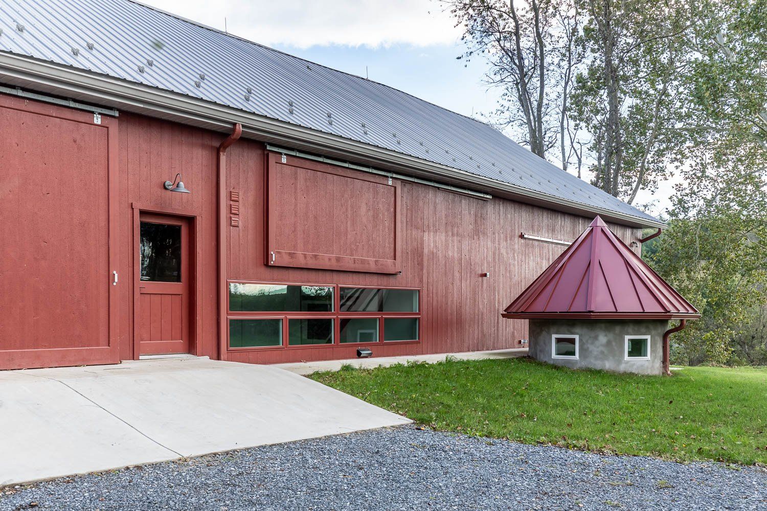 Red barn with sliding door and a small matching structure. Exterior view with green grass.