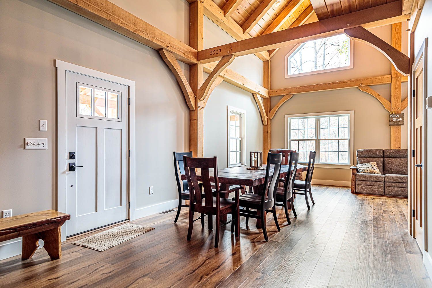 Dining room with wood beams, dark table, chairs, and white door.