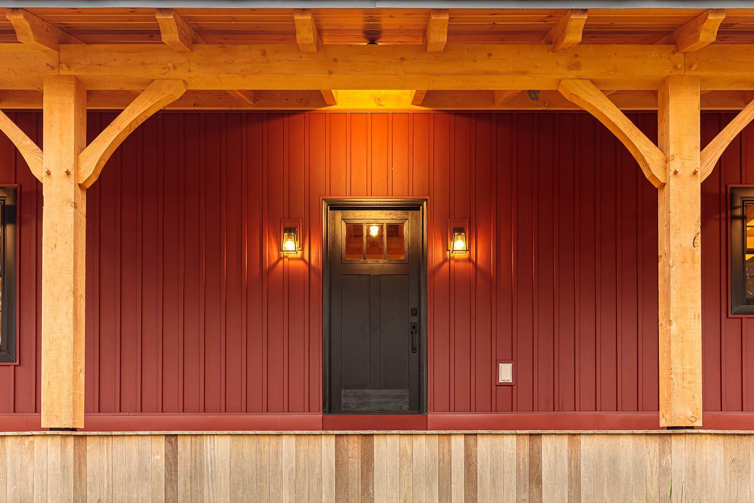 Red exterior with wooden beams, dark door, and two sconces.