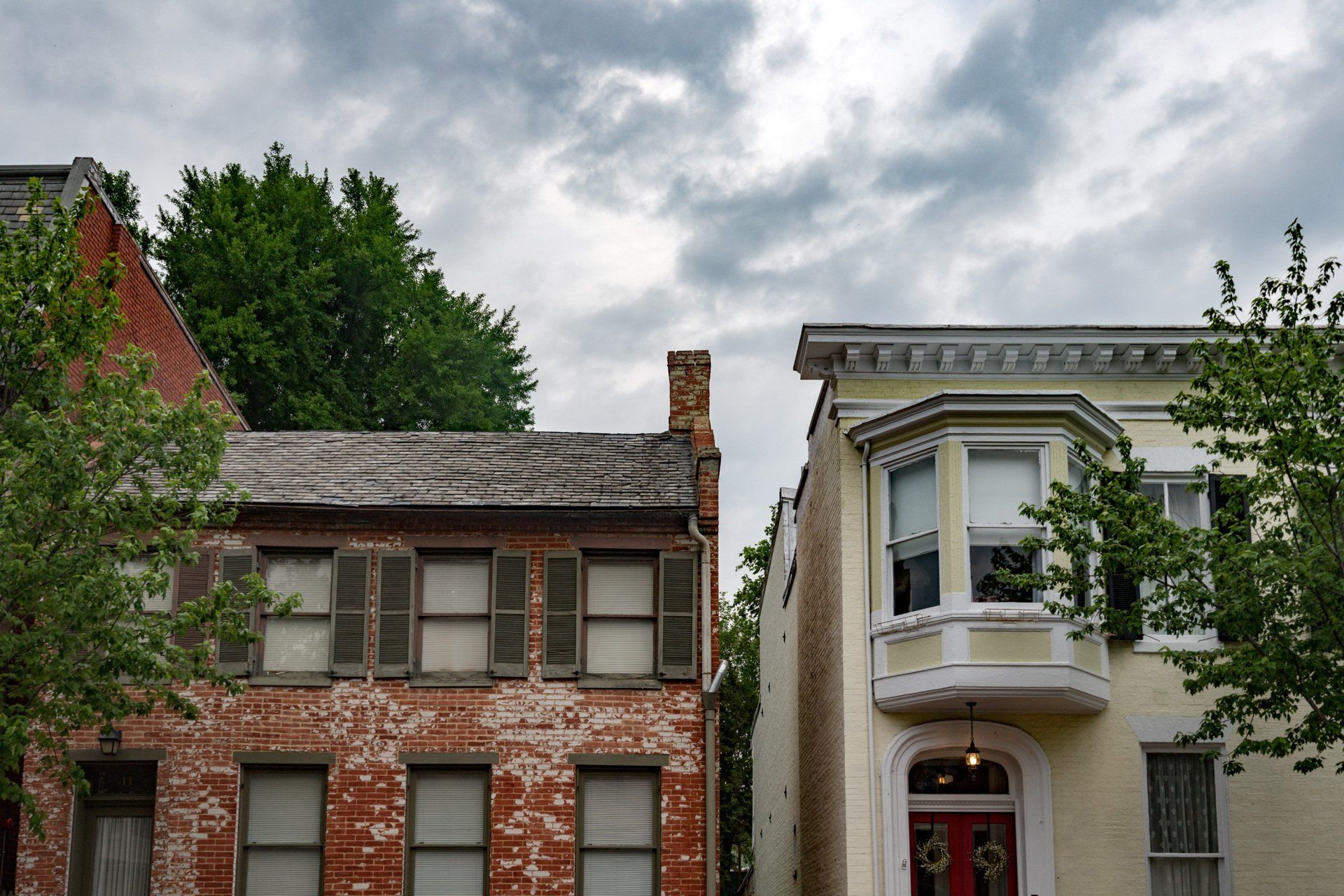 a brick building next to a white building with a bay window