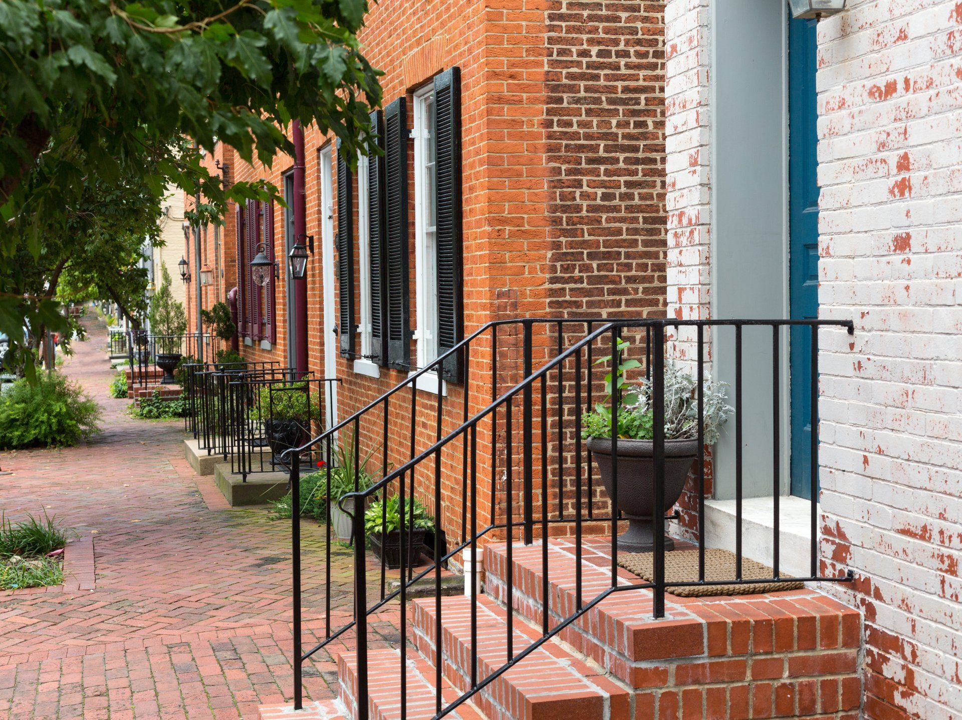 a brick building with a blue door and a black railing