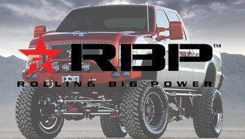 Red and white lifted truck with the RBIP logo, in a desert setting.