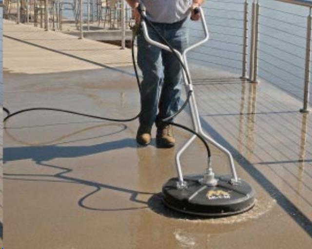 Person operating a floor-cleaning machine on a waterfront walkway