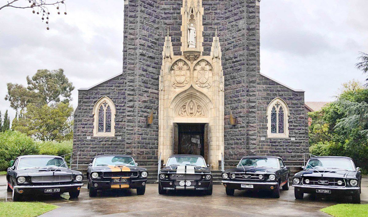 A group of cars are parked in front of a church.
