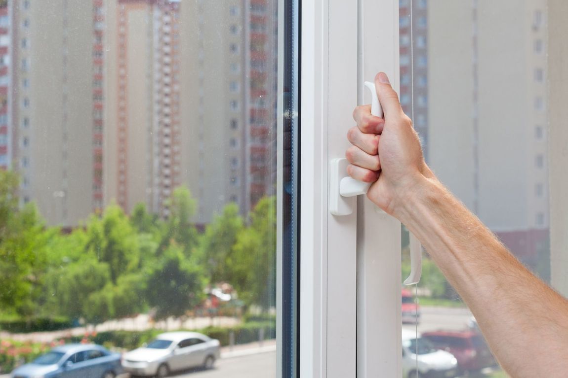 uomo mentre apre la finestra di casa in PVC