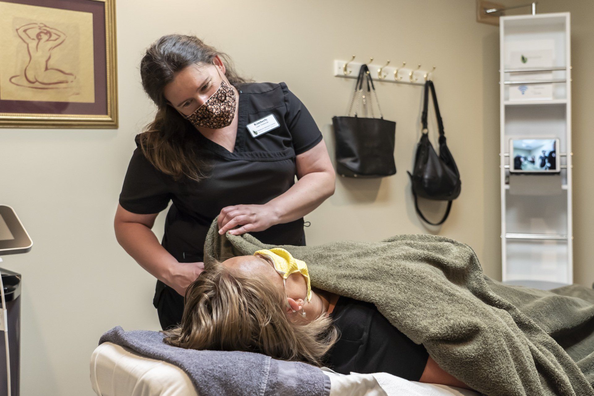 A woman wearing a mask is giving patient a blanket