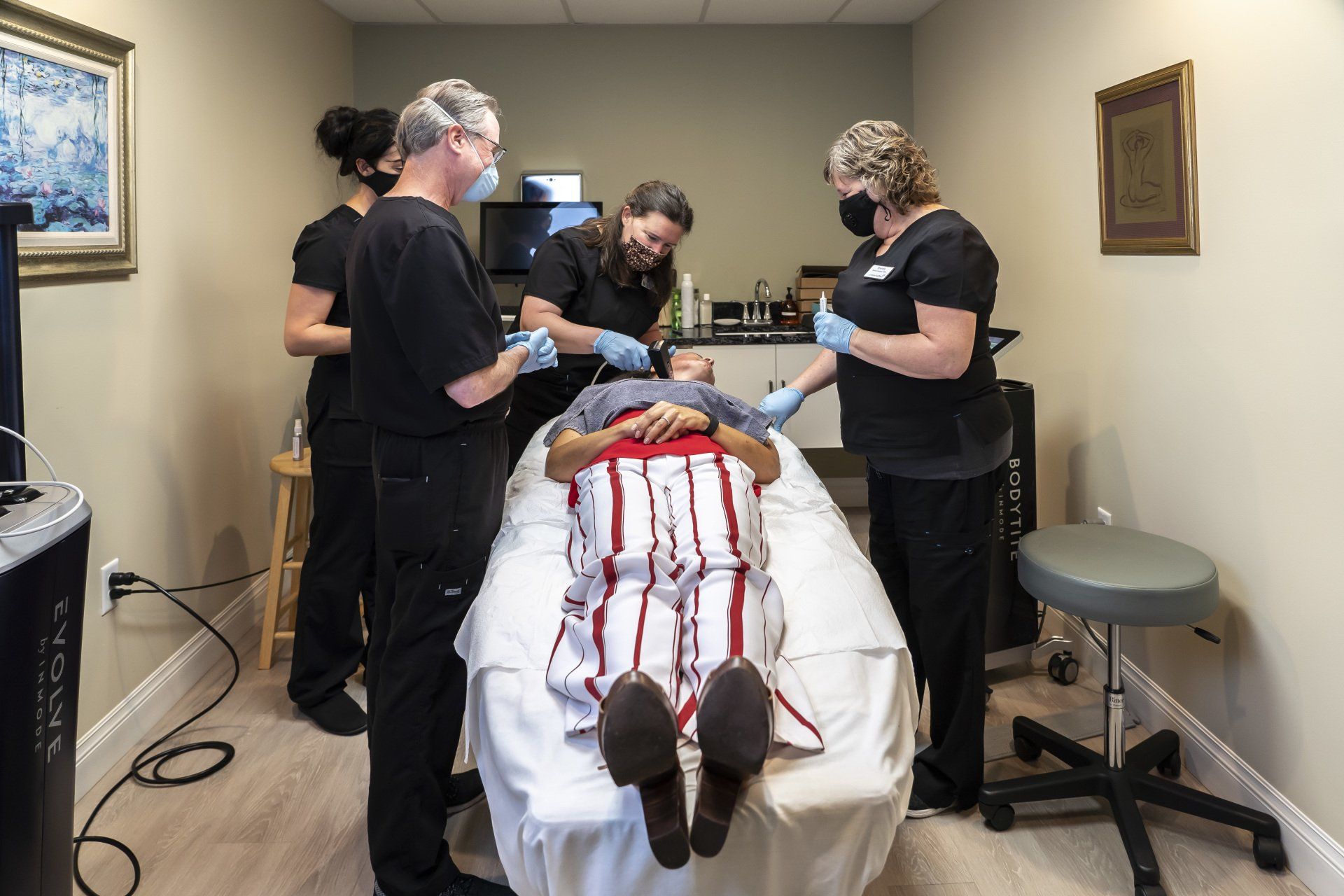 A group of people are standing around a patient laying on a bed.