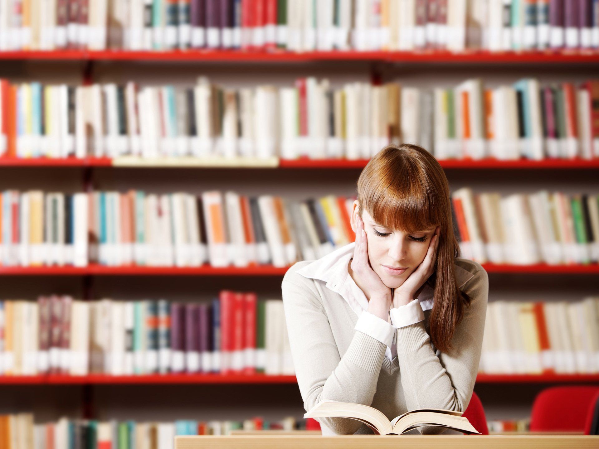 A woman is reading a book in a library