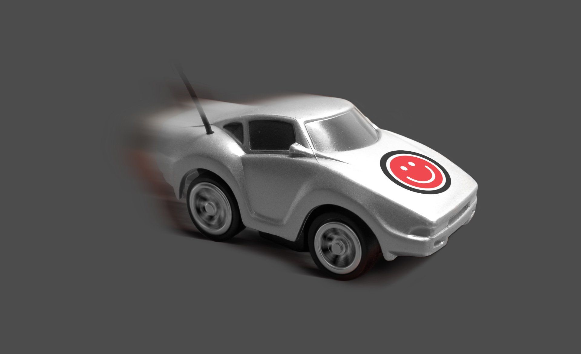 A white toy car with a red smiley face on the side