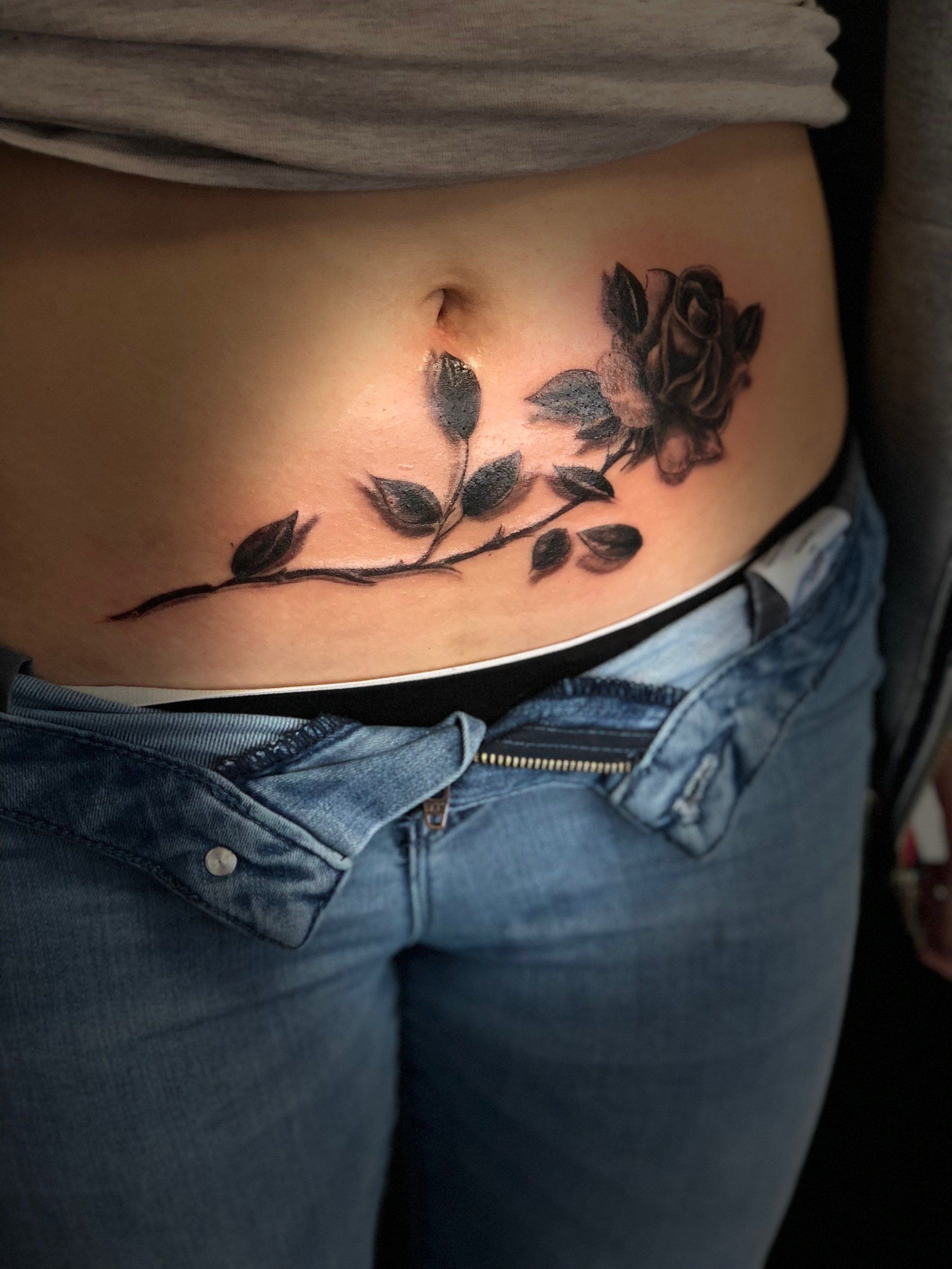 Eine Frau hat eine Rose auf dem Bauch tätowiert