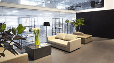 Office seating area with low cream sofas, square coffee tables and brown tiled floor