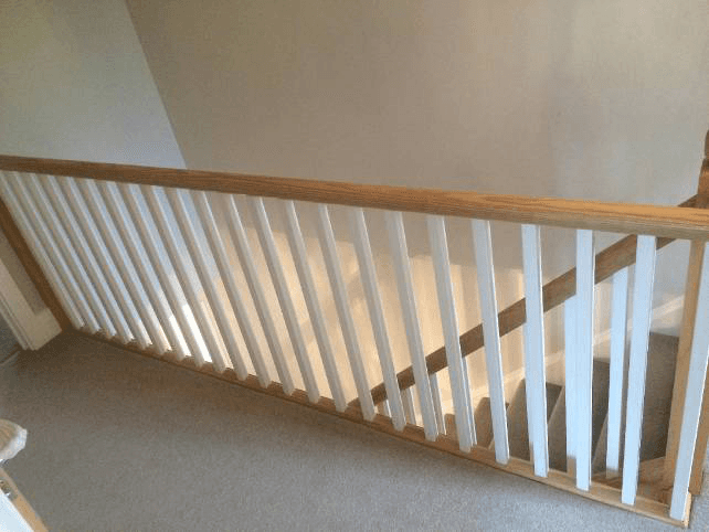 The top of a staircase with white and natural handrails