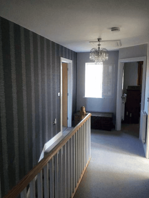 A landing with wooden rail, and dark brown stripe walls