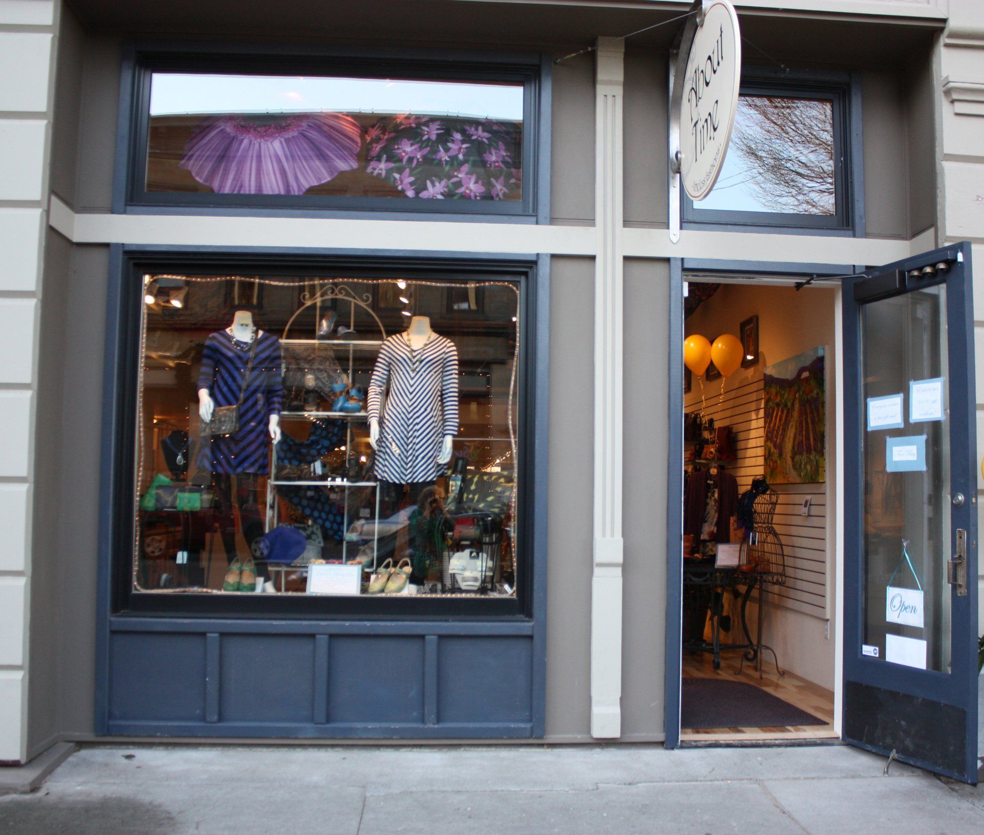 A store front with mannequins in the window and the door open