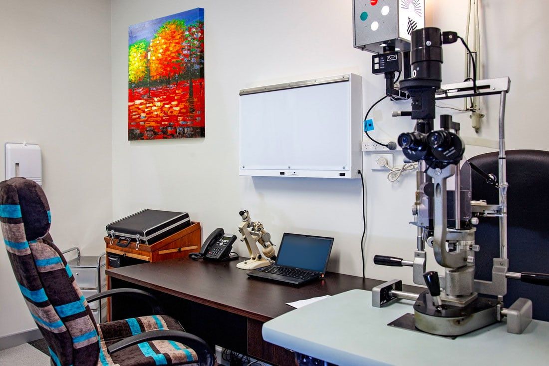 Office with a desk, chair, microscope, laptop, and whiteboard on a wall.