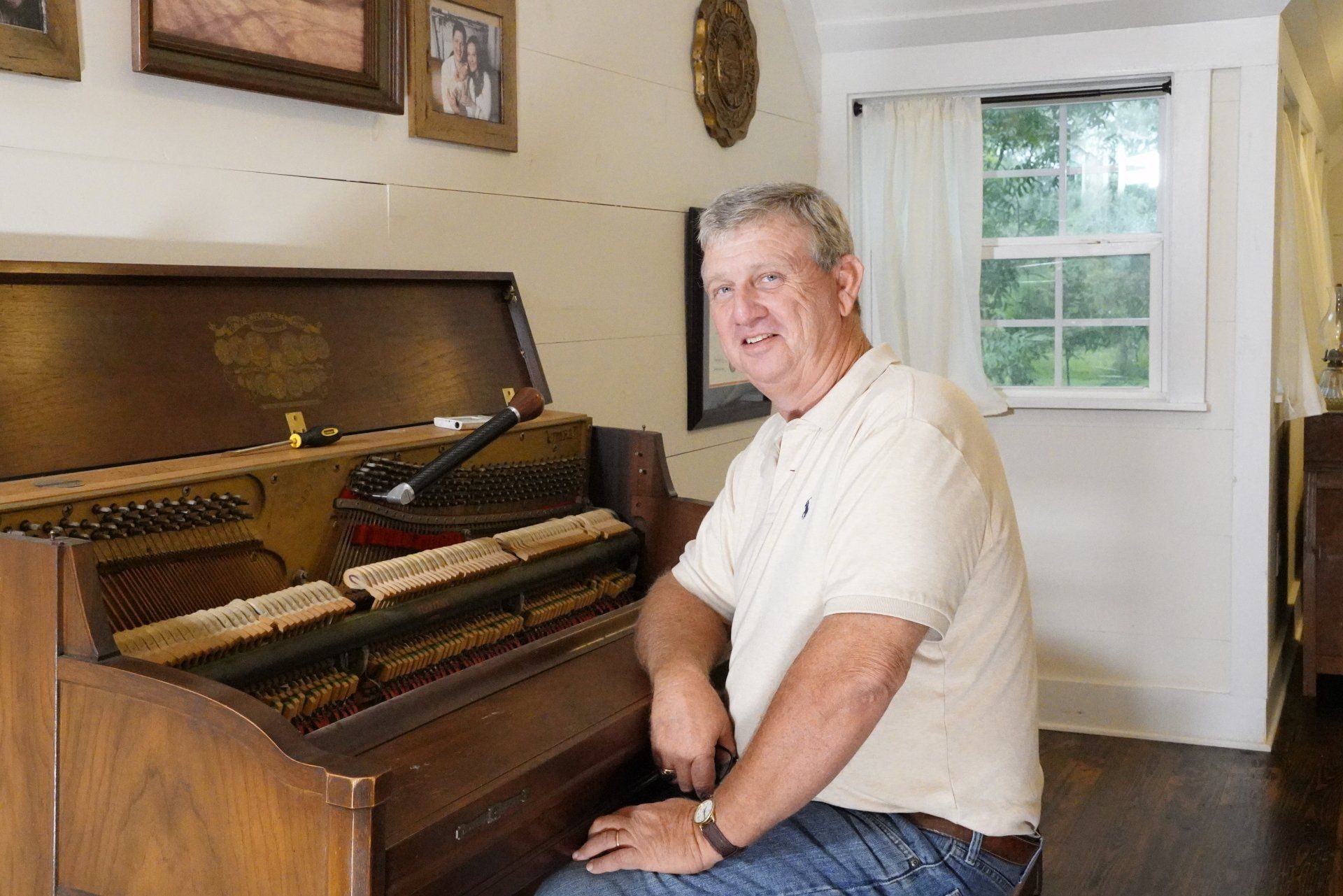 A man is sitting at a piano in front of a window.
