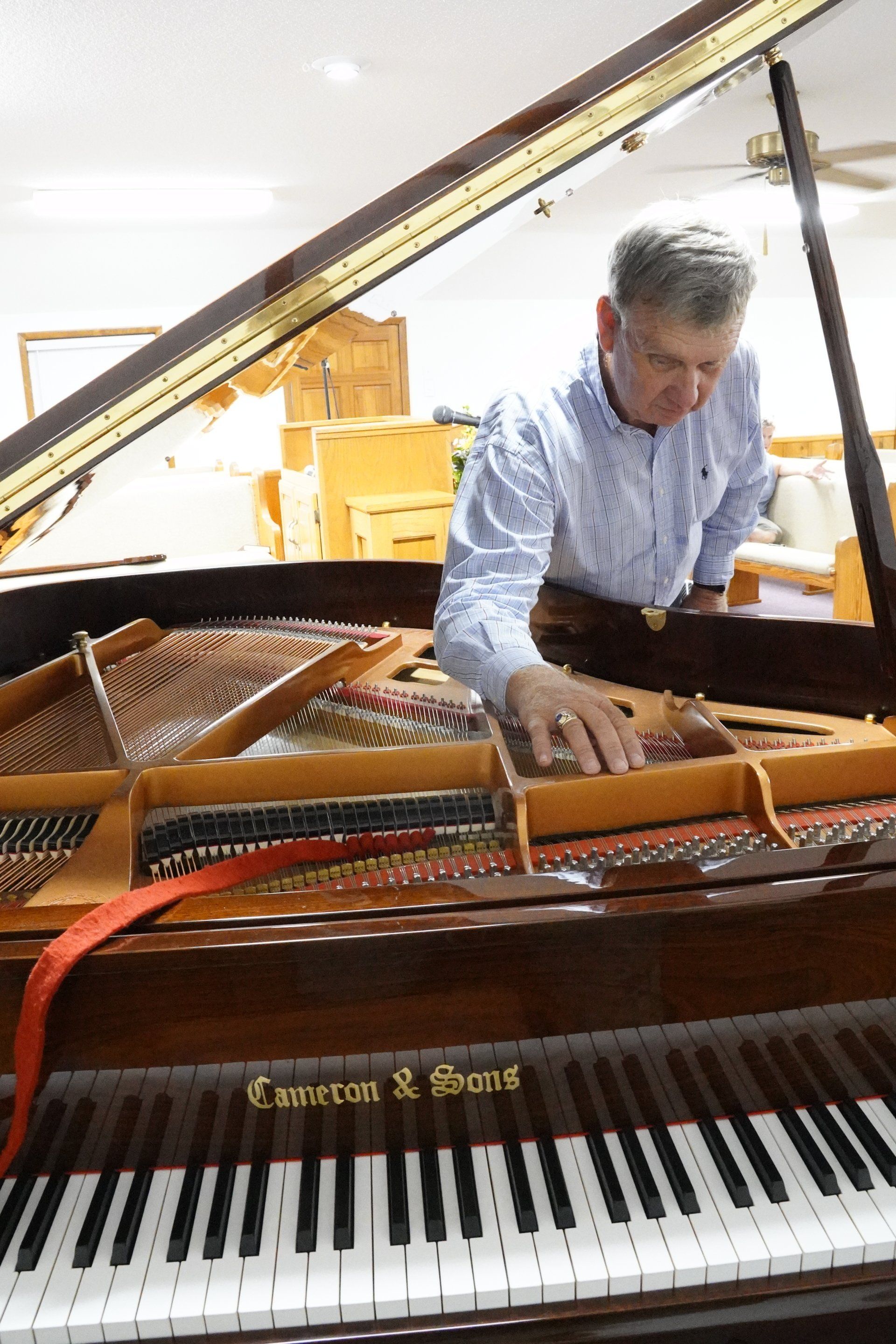 A man is working on a grand piano in a room.