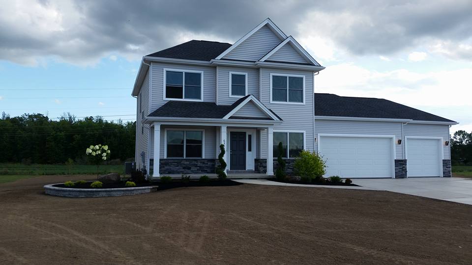 a large white house with a black roof and white garage doors