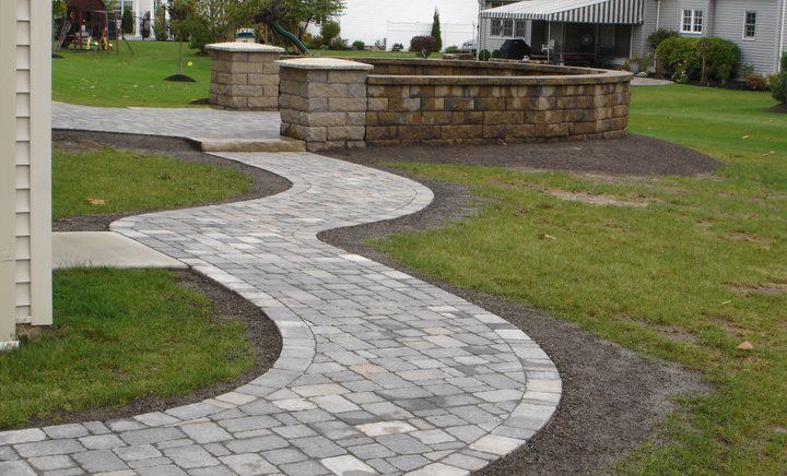 a brick walkway going through a lush green field .