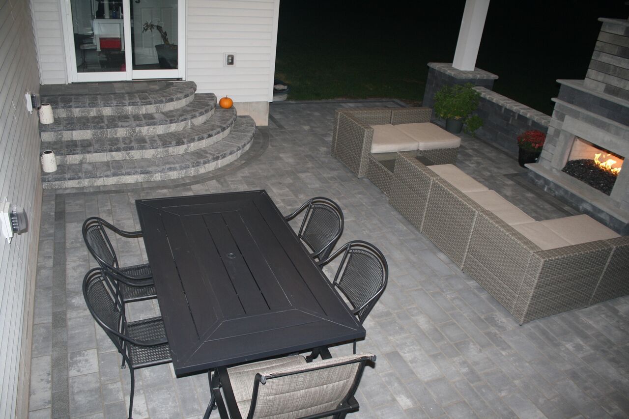 a patio with a table and chairs and a fireplace