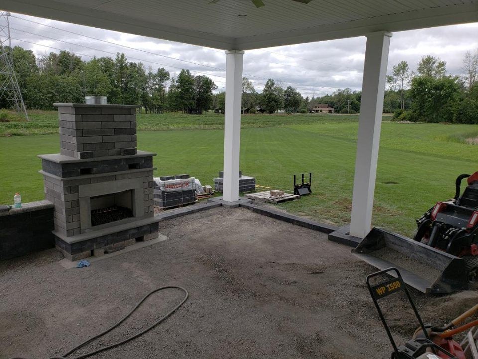 a patio with a fireplace and a golf course in the background .