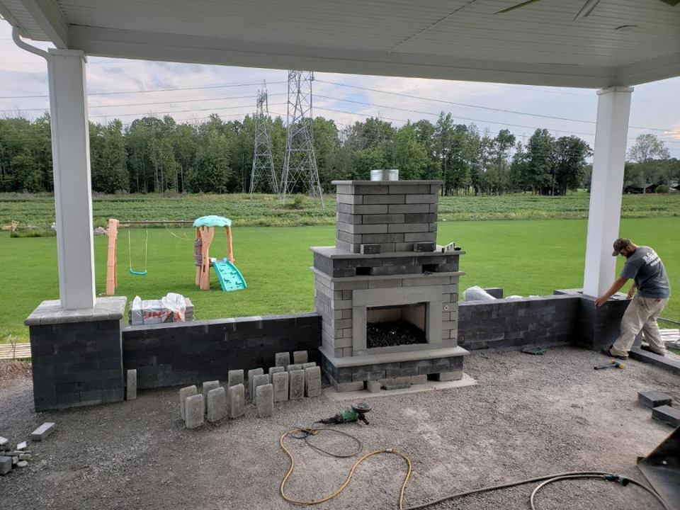 a man is working on a fireplace on a patio .