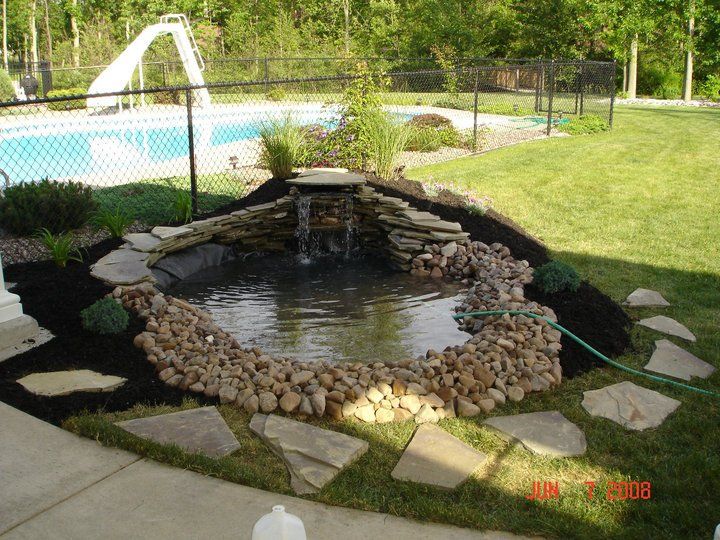 a pond in a backyard with a water slide in the background